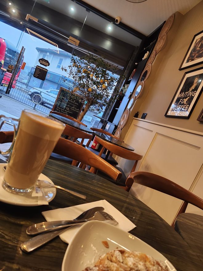 Latte and almond croissant on the marble table by the front window.