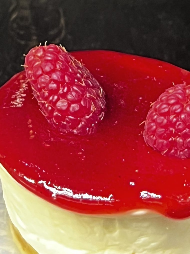 A raspberry-topped cheesecake slice.